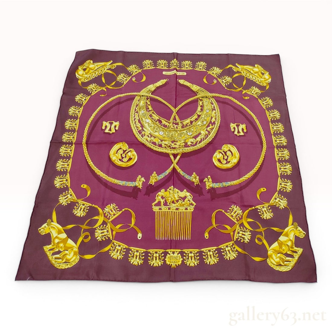 Hermes Les Cavaliers d'Or Silk Carre 90 Scarf in Burgundy: An Hermes silk scarf in the Les Cavaliers d'Or pattern, designed by Vladimir Rybaltchenko. This Carre 90 scarf is constructed from 100% silk twill and features a deep burgundy background. The graphic 