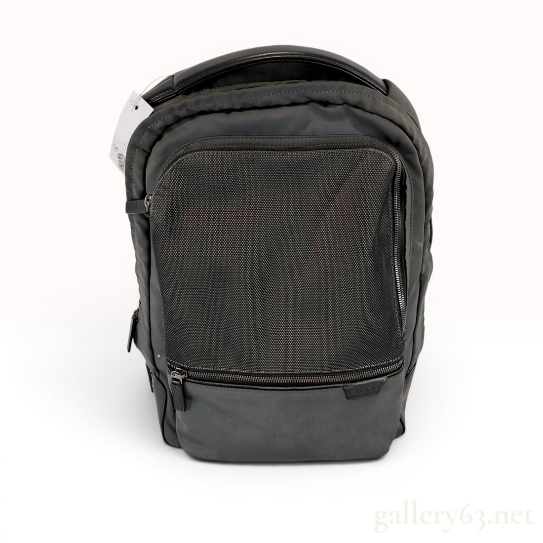 Tumi Harrison Bradner Backpack: A Tumi Bradner backpack from the Harrison collection, featuring a charcoal gray nylon exterior with a front mesh zip compartment and a reinforced black leather base. The backpack is constructed with a