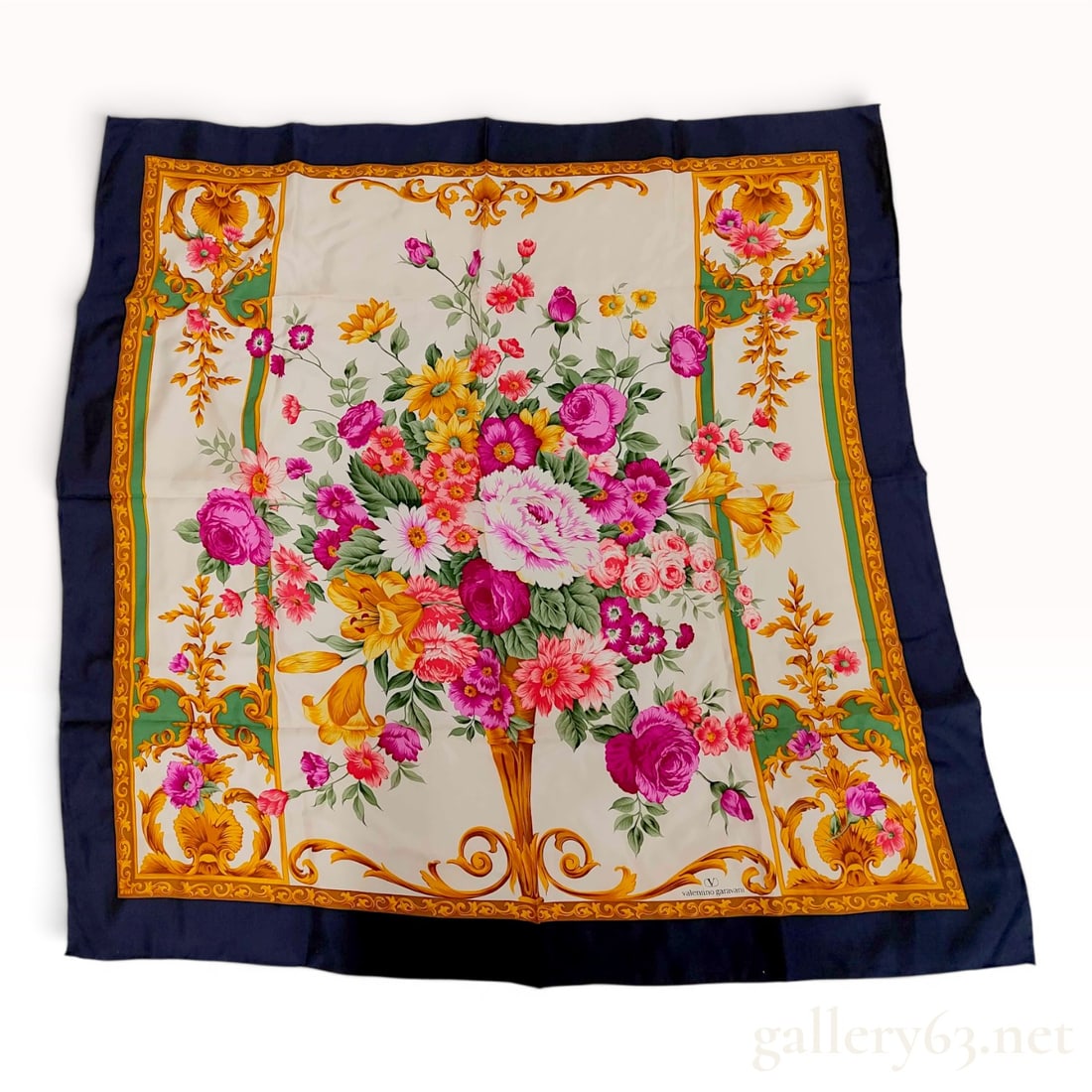 Valentino Garavani Floral and Baroque Motif Silk Scarf with Navy Border: A large square silk scarf by Valentino Garavani. The design features a central floral bouquet depicting roses, lilies, and daisies in vibrant shades of pink, red, and yellow, set against an off-white 