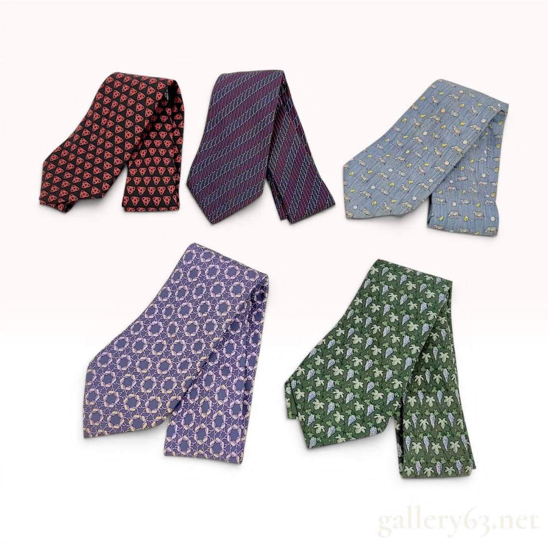 Lot of Five Hermes Silk Neckties: A collection of five designer silk neckties from Hermes. The assortment includes various patterns and colorways: one tie features a repeating red interlocking trefoil or stylized knot pattern on a bla