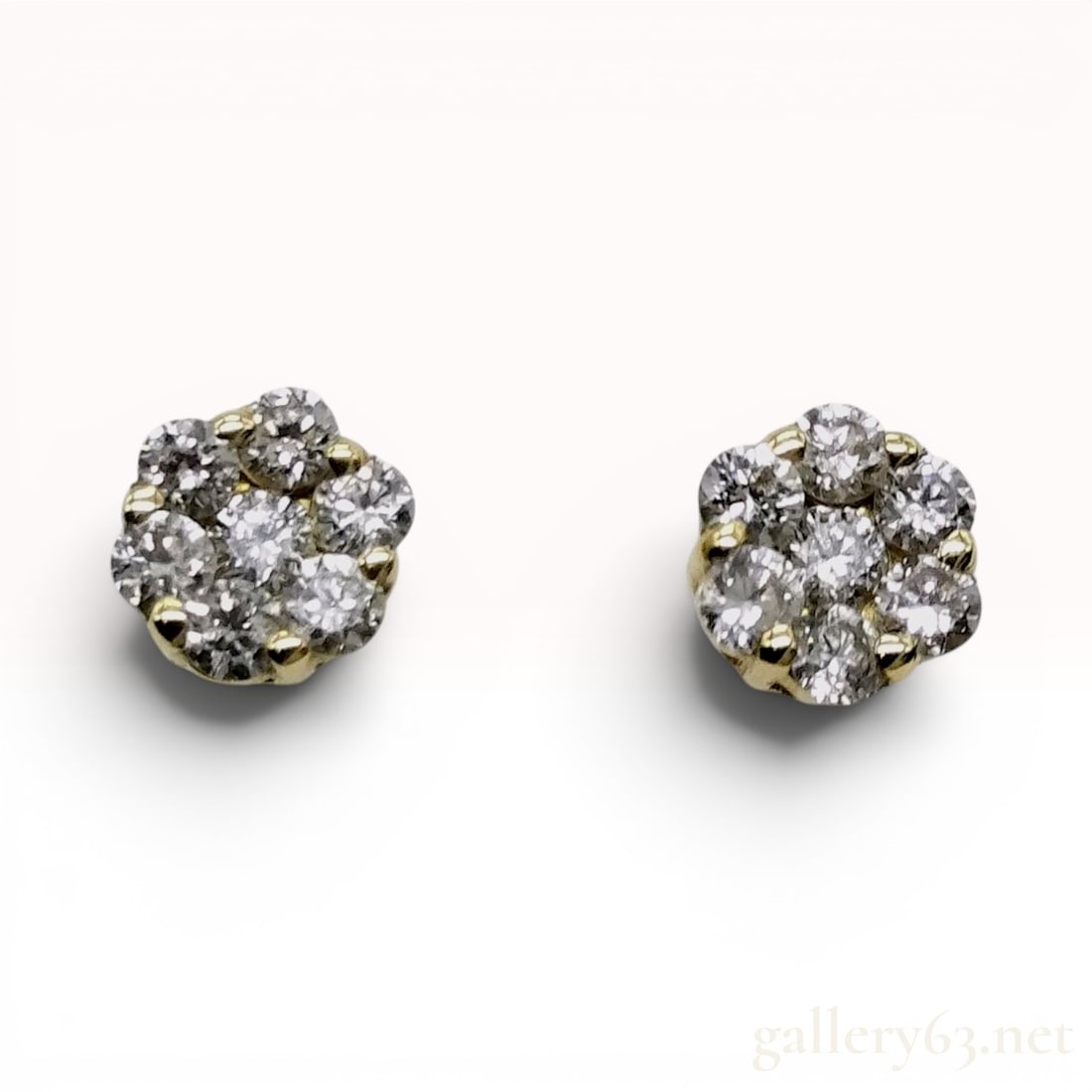 A Pair of Diamond Flower Cluster Stud Earrings in 18K Yellow Gold: This is a matched pair of diamond cluster stud earrings set in 18 karat yellow gold. Each earring features a floral-style arrangement of seven round brilliant-cut diamonds, with one central stone enci