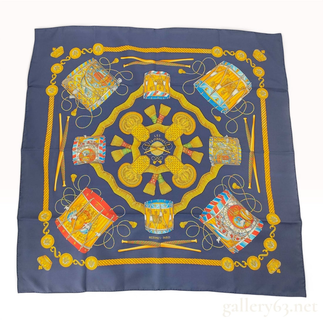Hermes Les Tambours Silk Scarf by Joachim Metz: This is an authentic Hermes silk square scarf titled Les Tambours, designed by artist Joachim Metz and first issued in 1989. The scarf is constructed from 100 percent silk twill with hand-rolled hems.