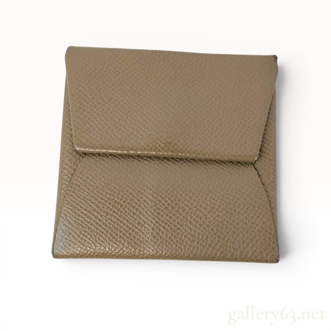 Hermes Bastia Epsom Leather Coin Purse: Hermes Bastia coin purse, a minimalist accessory crafted from a single piece of grained Epsom calfskin leather. The leather is finished in a taupe colorway. Its design features a series of folds that 