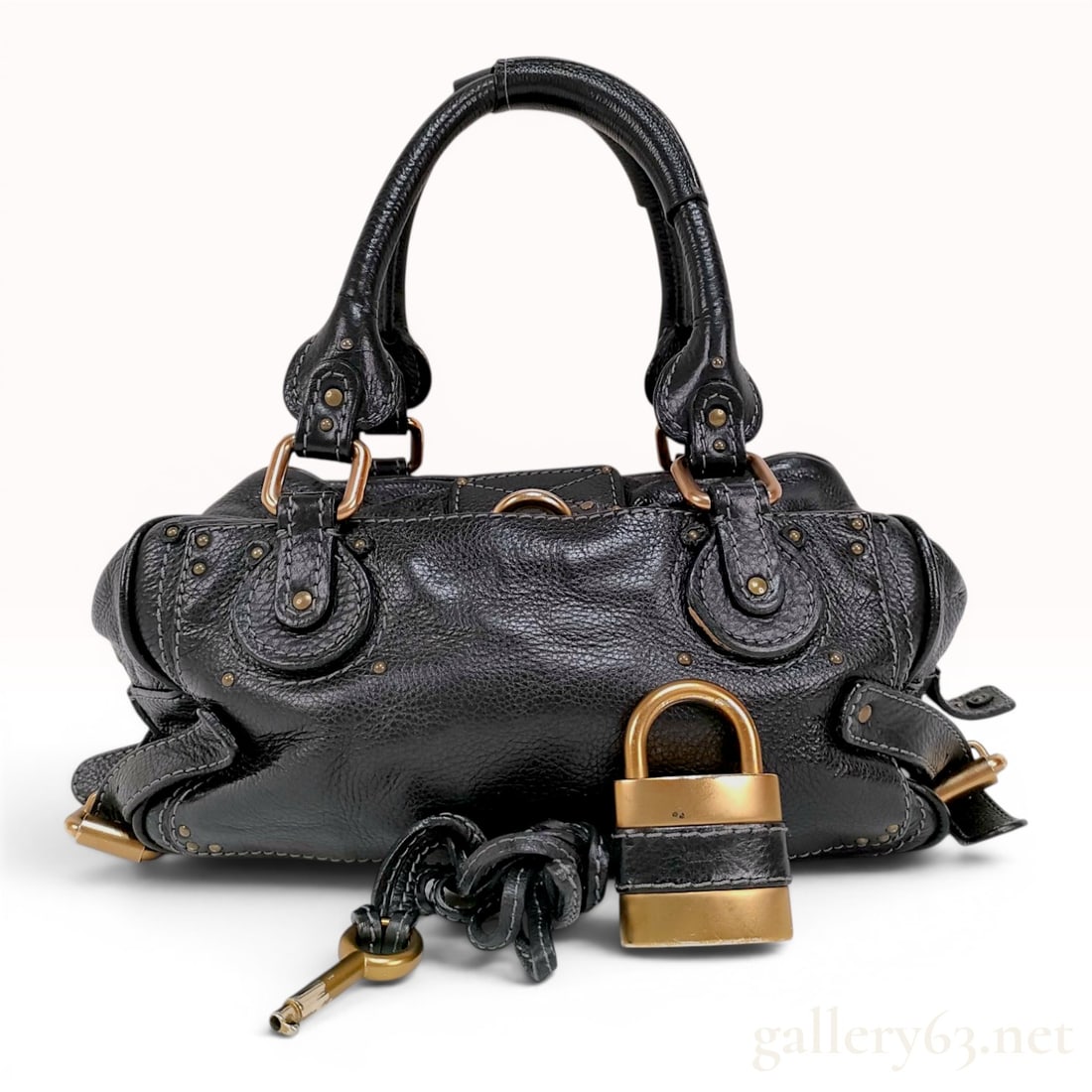 Chloe Paddington Black Pebbled Leather Satchel: A Chloe Paddington satchel crafted from black pebbled calfskin leather featuring heavy-duty brushed brass hardware. This handbag is designed with dual rolled leather top handles and a double zipper to