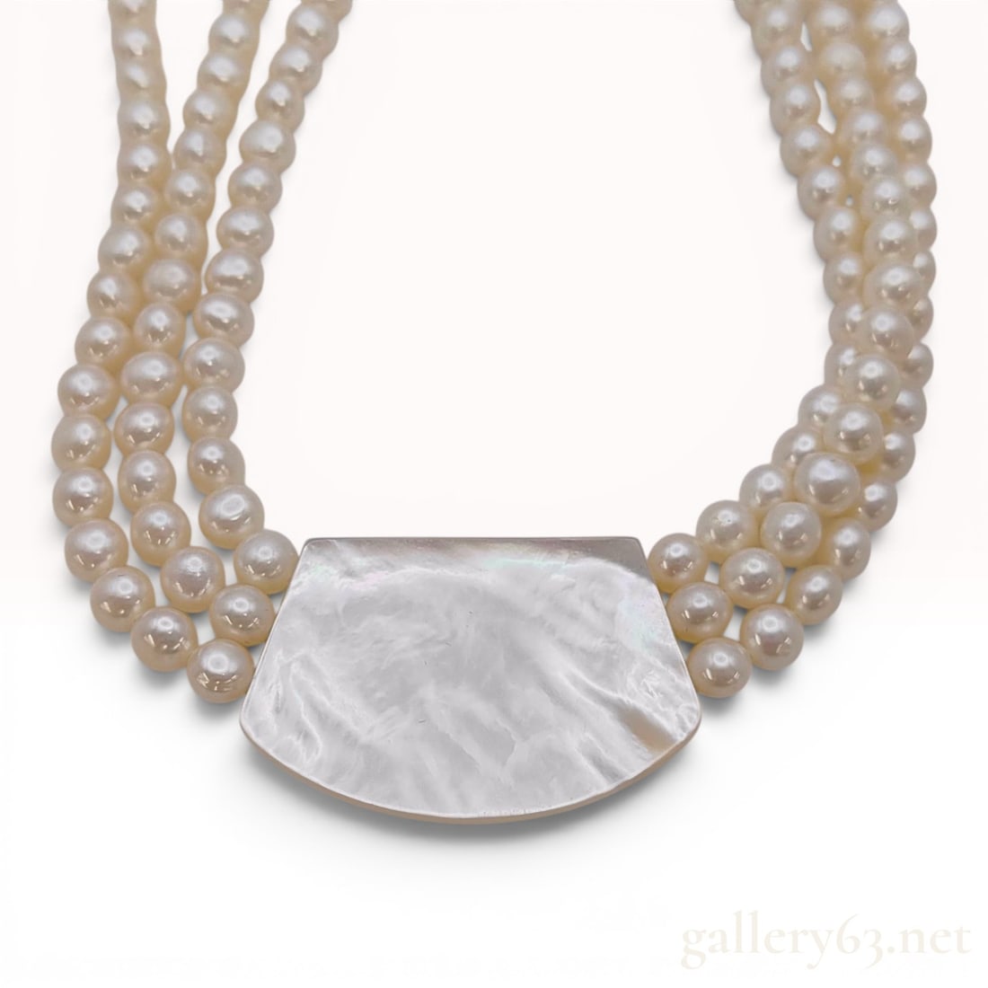Triple-Strand Freshwater Pearl Necklace with Mother-of-Pearl Centerpiece: This vintage triple-strand collar necklace features three rows of semi-round white freshwater cultured pearls. The necklace is centered by a large, shield-shaped plaque of iridescent white mother-of-p