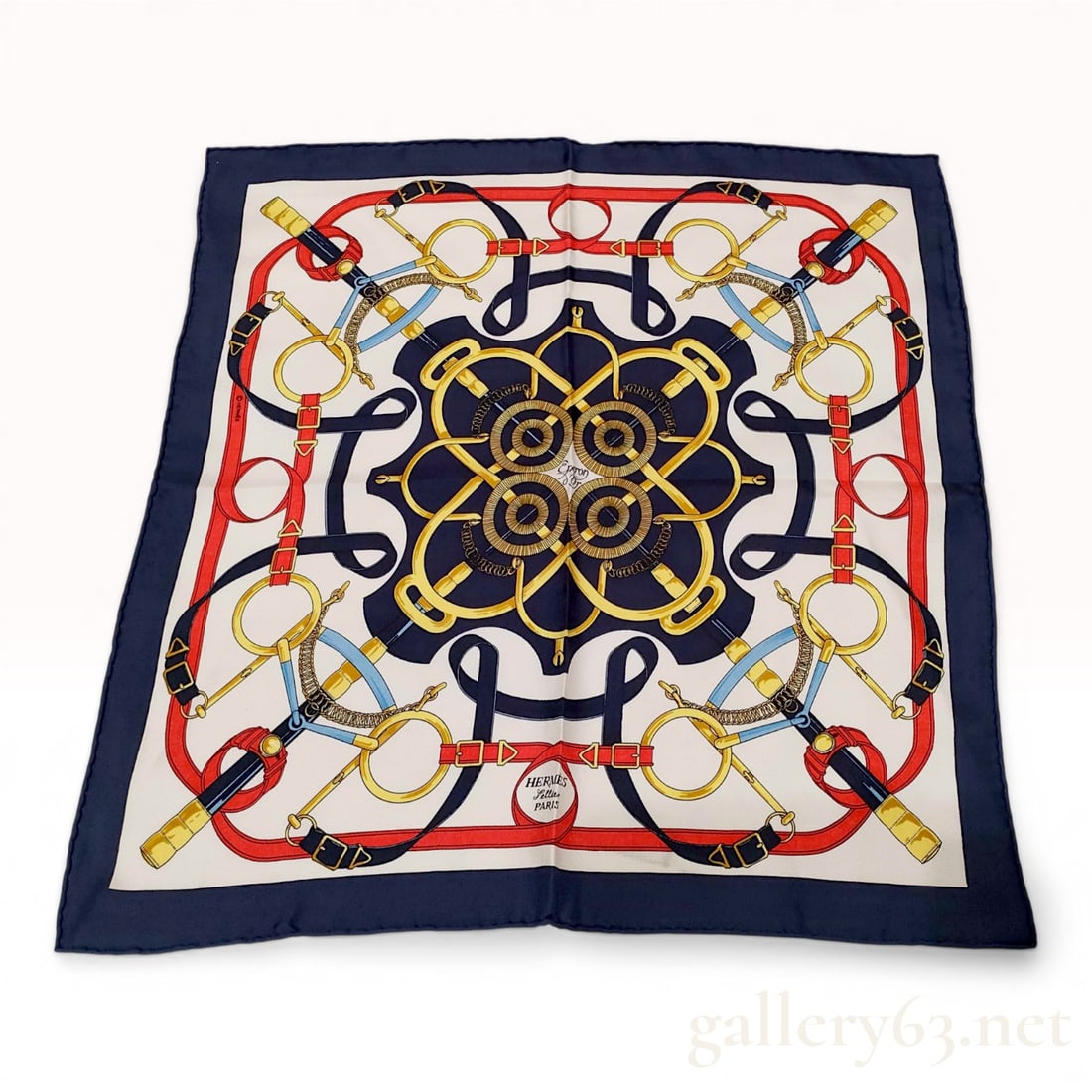 Hermes Eperon d'Or Silk Gavroche Scarf: Hermes silk gavroche scarf in the Eperon d'Or pattern designed by Henri d'Origny. The equestrian motif features an arrangement of spurs, bits, and leather straps in navy blue, red, gold, and light blu