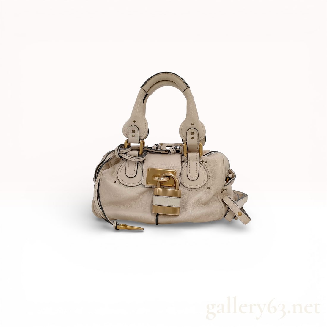 Chloe Paddington Leather Satchel in Cream: Chloe Paddington satchel crafted from cream pebbled leather with brushed gold-tone brass hardware. The design features a signature oversized functional padlock, a leather-bound key, and double rolled 