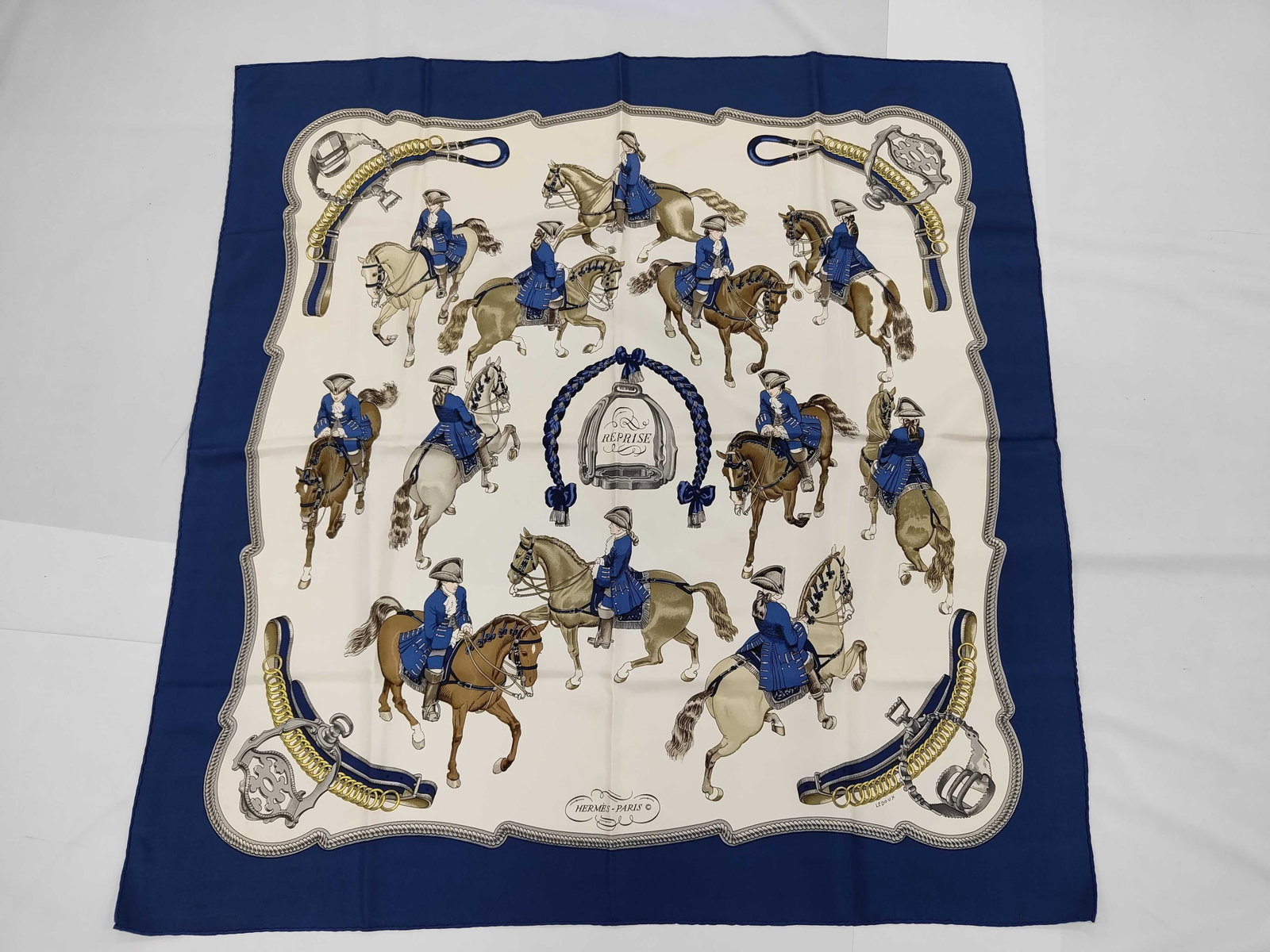 Hermes Reprise Silk Scarf by Philippe Ledoux: This square scarf is crafted from silk twill and features the Reprise pattern designed by Philippe Ledoux for Hermes. The equestrian-themed design depicts riders in 18th-century style blue dressage un