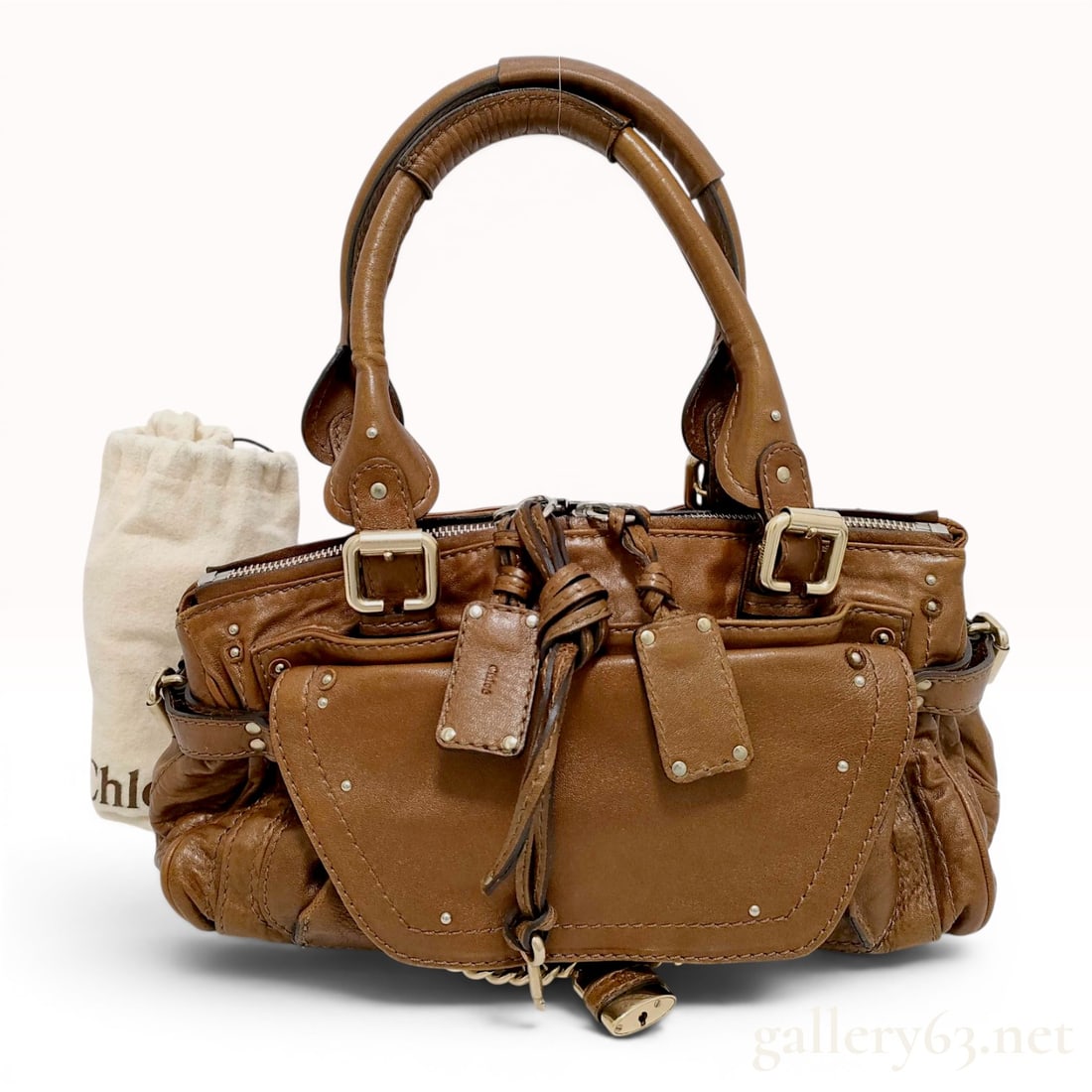 Chloe Brown Leather Paddington Handbag: Chloe Paddington handbag bearing the embossed mark of Chloe and featuring the iconic oversized brass-tone padlock and key. This satchel is constructed from brown pebbled leather with decorative contra