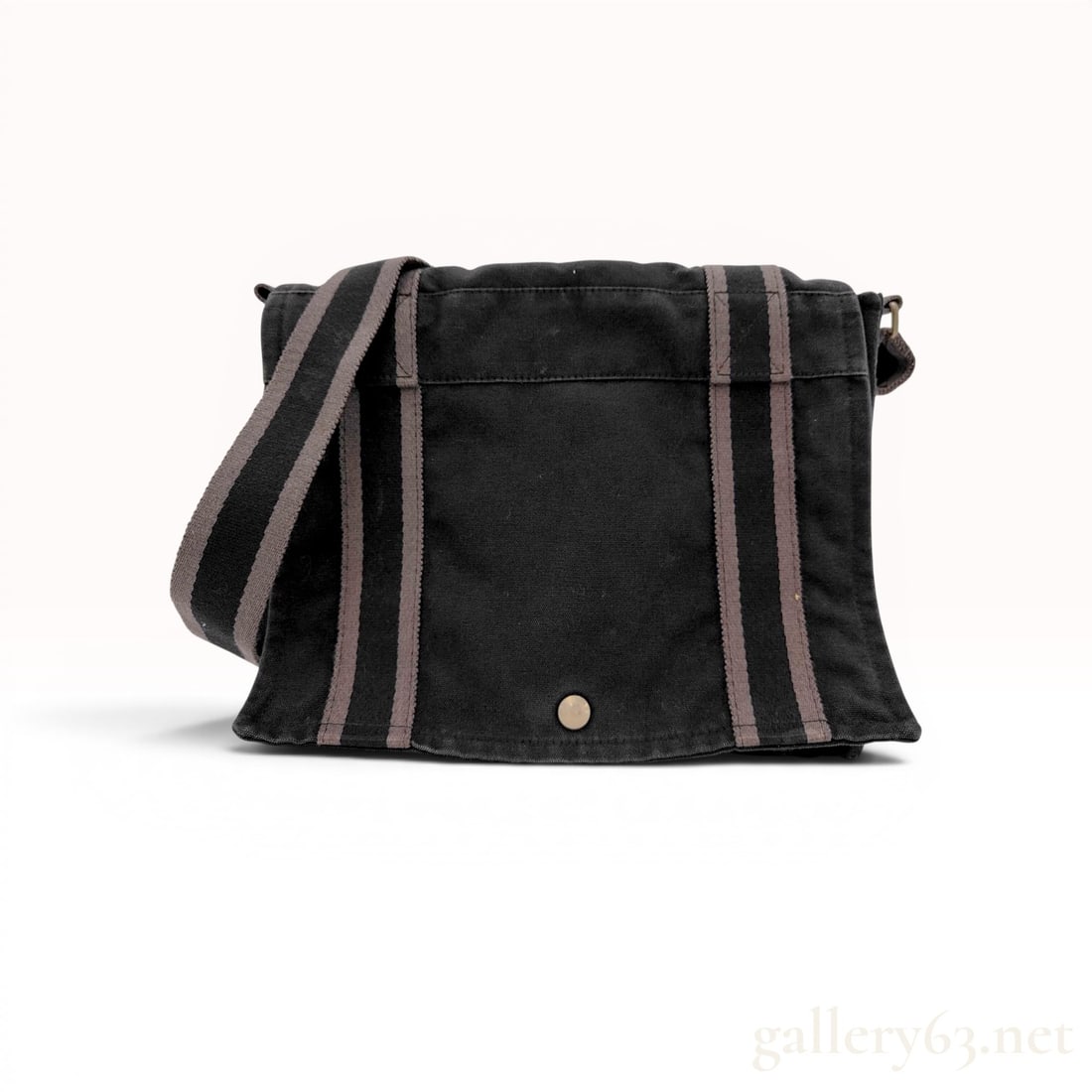 Hermes Herline Black Canvas Messenger Bag: Hermes Herline messenger bag in black canvas. Features signature grey striped webbing, a top flap with a metallic snap closure, and a black canvas-lined interior with a zippered pocket and contrasting