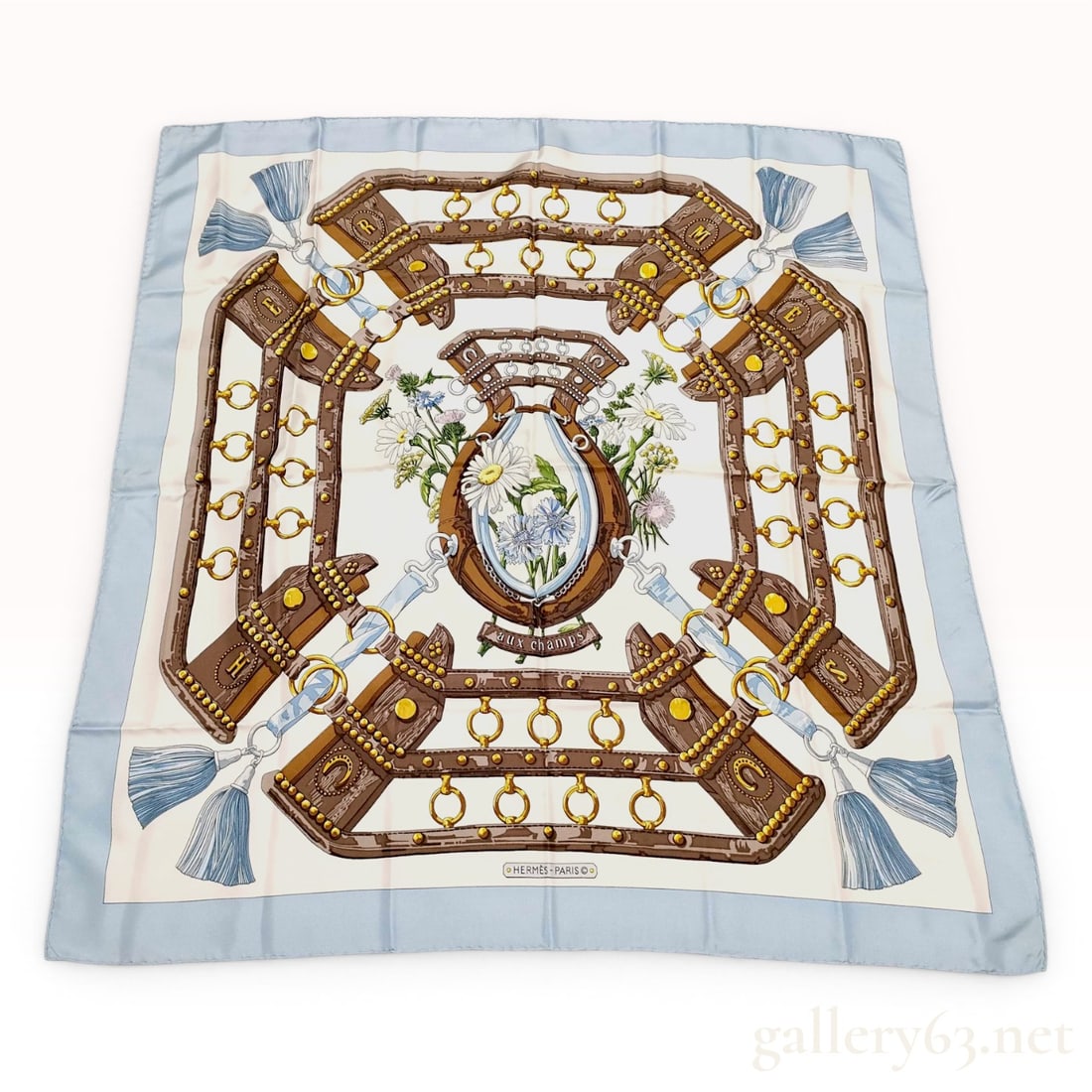 Hermes Aux Champs Silk Twill Scarf: A silk twill scarf by Hermes featuring the Aux Champs pattern designed by artist Caty Latham. The design features an equestrian theme with detailed brown leather horse bridles and straps accented with
