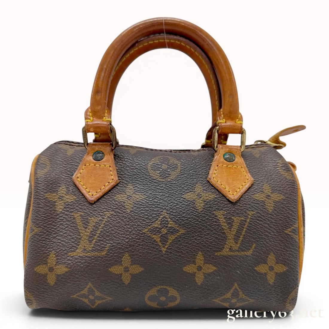 Louis Vuitton Monogram Mini Speedy HL Bag: This Louis Vuitton Mini Speedy HL handbag is constructed from the brand signature monogram coated canvas with natural vachetta leather rolled top handles and trim. This miniature accessory features a 