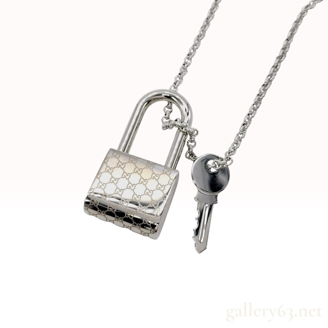 Gucci Padlock and Key Pendant Necklace Sterling Silver: Gucci padlock and key pendant necklace. Features a silver (sterling) metal cable chain with a spring ring clasp, accented by an engraved GG monogram padlock pendant and an attached key charm. Includes