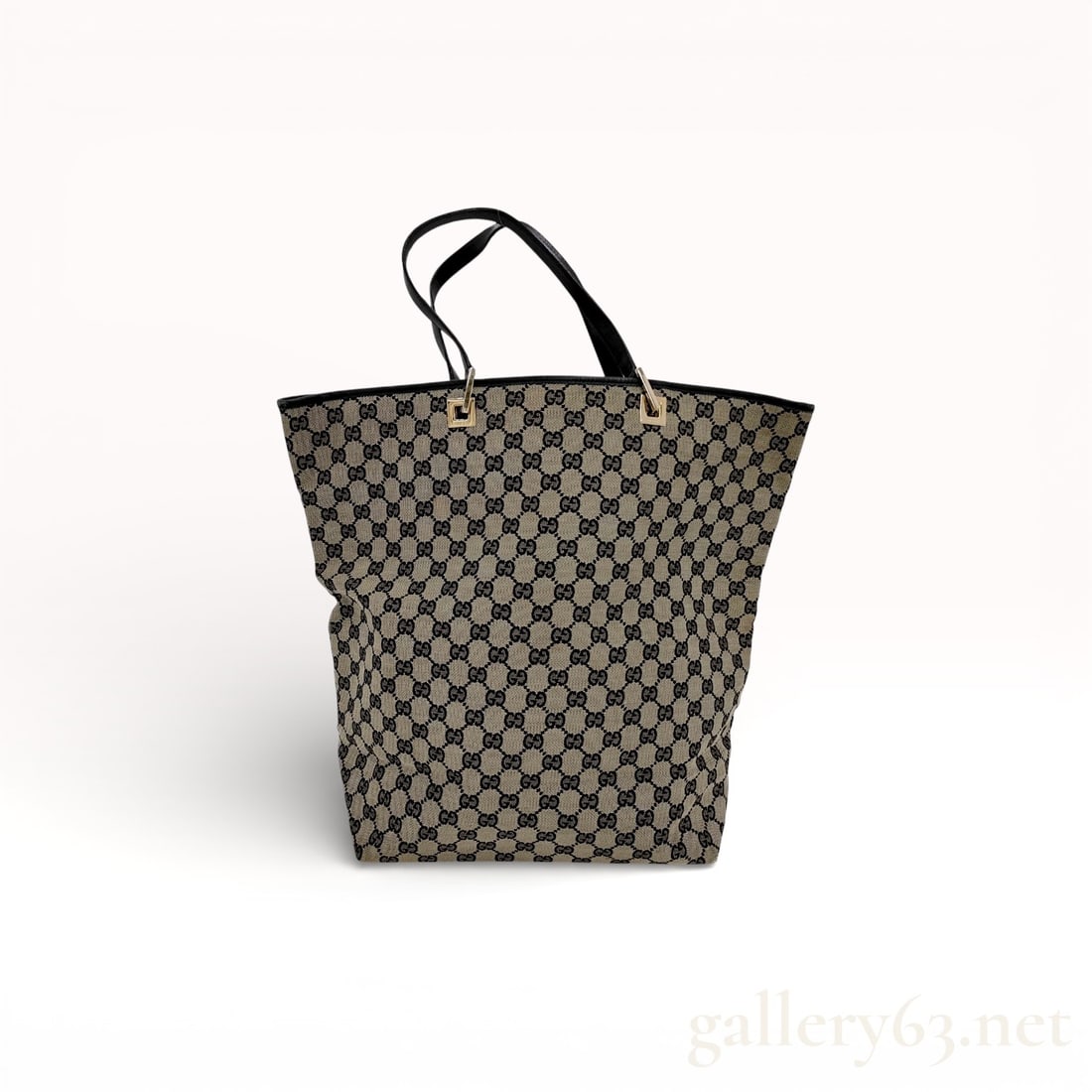 Gucci GG Monogram Canvas Tote Bag with Black Leather Trim: Gucci GG monogram canvas tote bag featuring beige and black woven textile with black leather handles and base. The design includes gold-tone hardware with square handle mounts engraved with Gucci bran