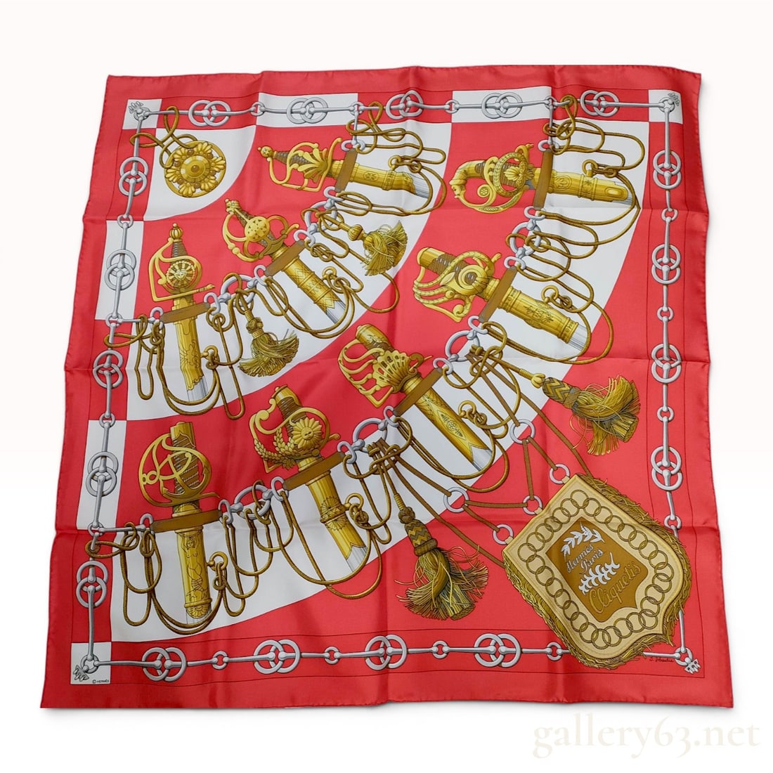 Hermes Cliquetis Silk Scarf by Julia Abadie in Red and White: A vintage Hermes Paris silk scarf featuring the Cliquetis pattern, designed by artist Julia Abadie. The design depicts various ceremonial military sabers and swords with ornate golden hilts and hangin