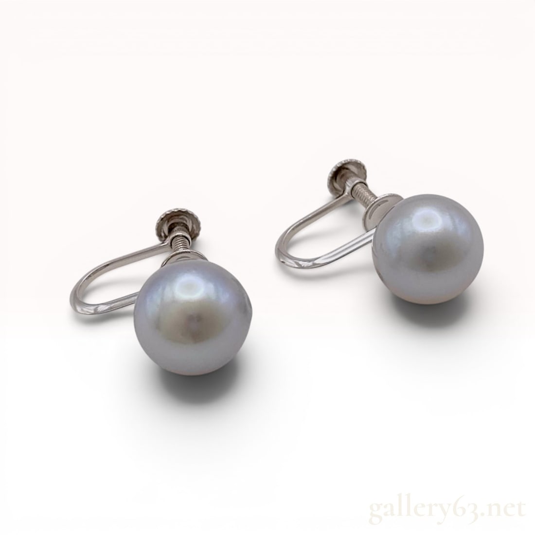 A Pair of Grey Cultured Pearl and 14 Karat White Gold Screw-Back Earrings: A matched pair of screw-back earrings featuring two spherical grey cultured pearls. Each pearl exhibits a silver-grey body color with high luster and a smooth surface. The pearls are set into 14 karat