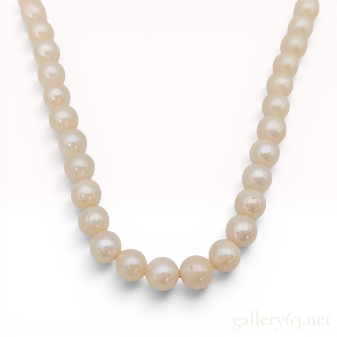 Graduated Akoya Cultured Pearl Strand Necklace with Silver Clasp: A single strand graduated cultured pearl necklace. The necklace features hand-knotted, semi-round Akoya pearls with a creamy-white body color and visible luster. The pearls are graduated in size, with