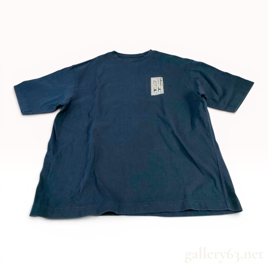 Gucci Navy Blue Cotton Graphic Short-Sleeve T-Shirt: This short-sleeve crewneck T-shirt by Gucci is crafted from navy blue cotton jersey. The front left chest features a small white rectangular graphic containing the brand name in a stylized grid and th