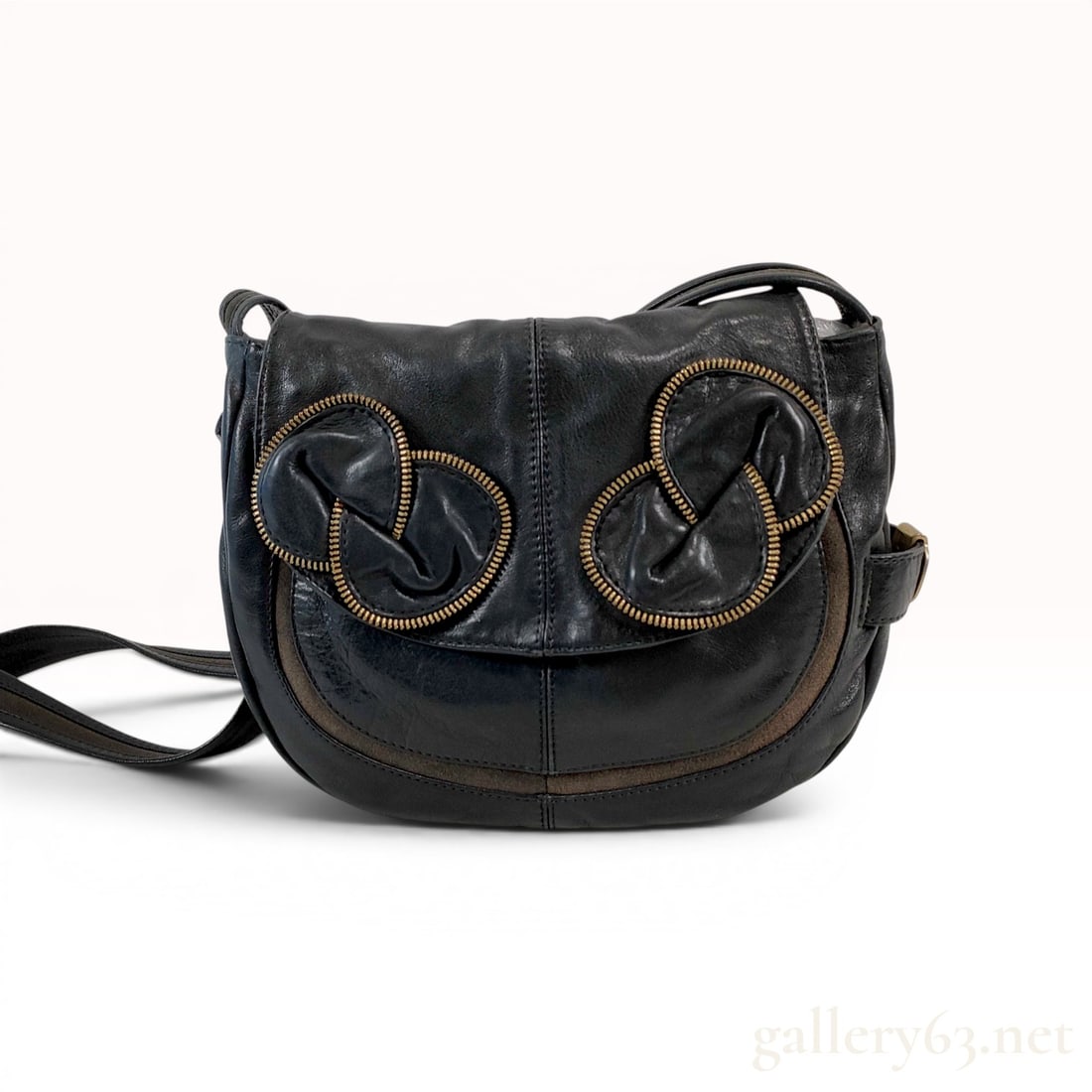 See by Chloe Black Leather Zip-Knot Saddle Bag: See by Chloe saddle-style crossbody bag in black pebbled leather with taupe suede accents. The front flap features decorative gold-tone zip-knot motifs and a magnetic closure, while the adjustable sho