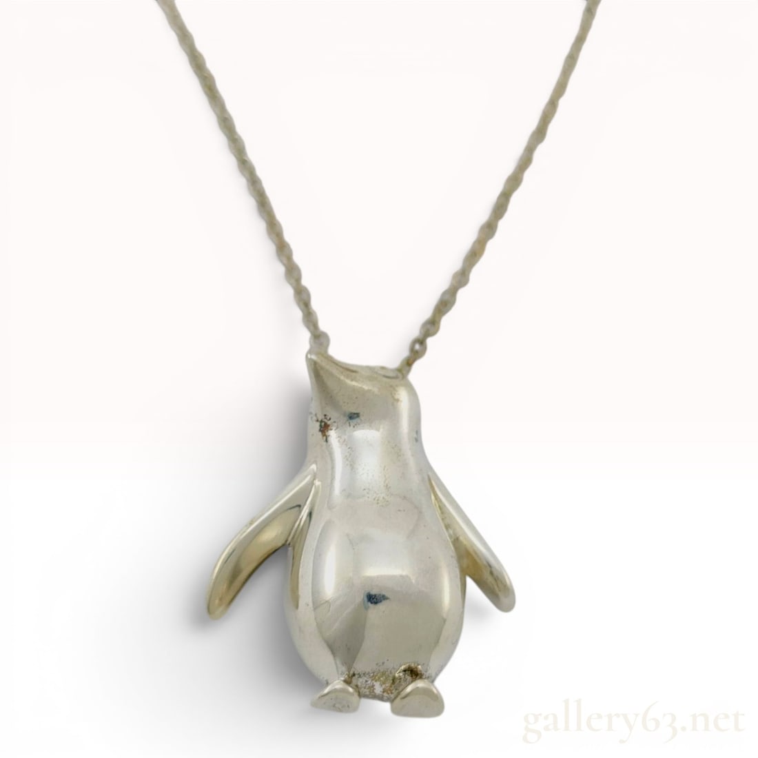 Tiffany and Co. Sterling Silver Penguin Pendant Necklace: This sterling silver necklace features a three-dimensional penguin pendant by Tiffany and Co. The pendant is designed as a stylized penguin with a polished exterior and a hollowed reverse side. It is 