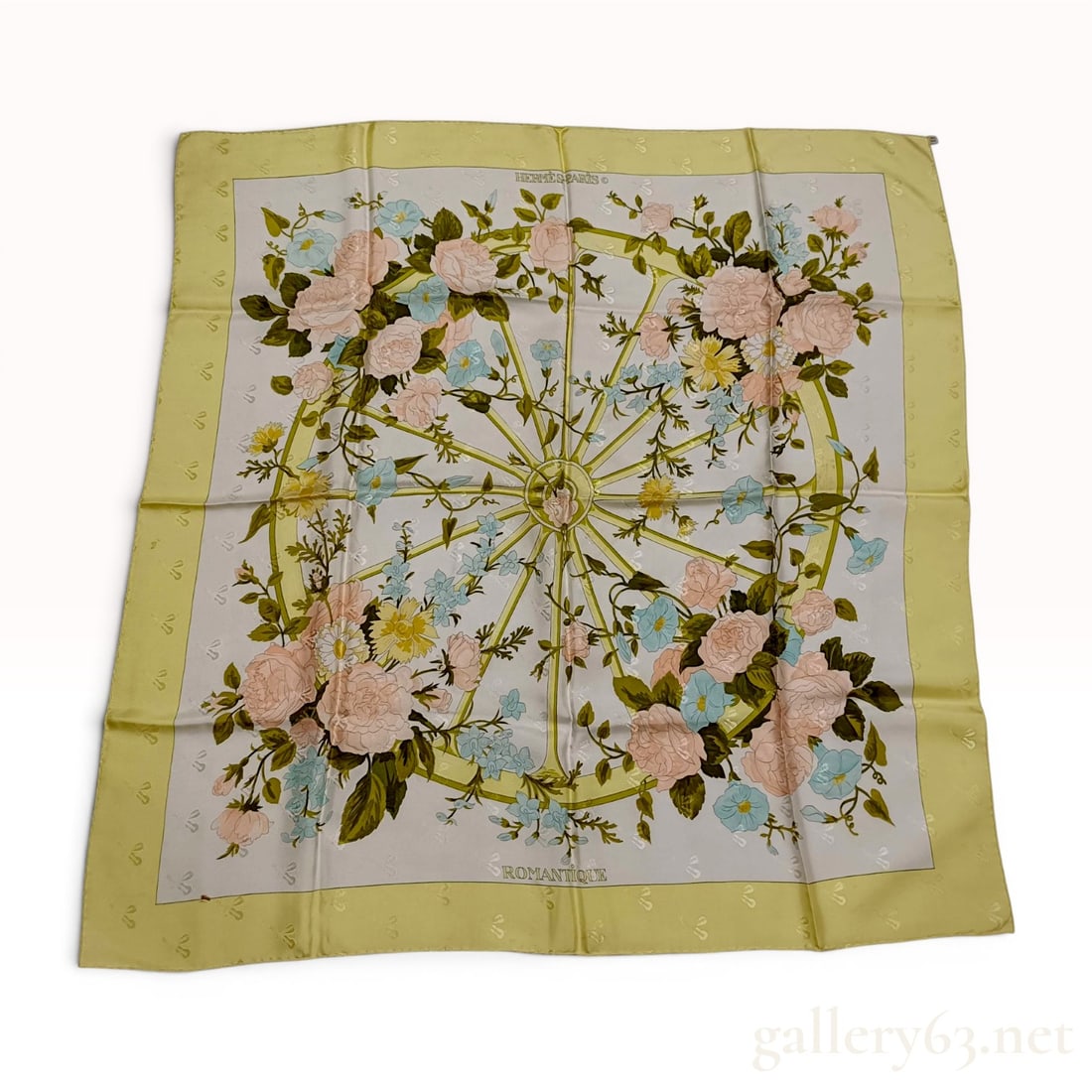 Hermes Romantique Silk Jacquard Scarf by Maurice Tranchant: This square silk scarf features the Romantique pattern, designed by Maurice Tranchant for Hermes and first issued in 1973. The central motif depicts a wagon wheel interwoven with a floral arrangement 