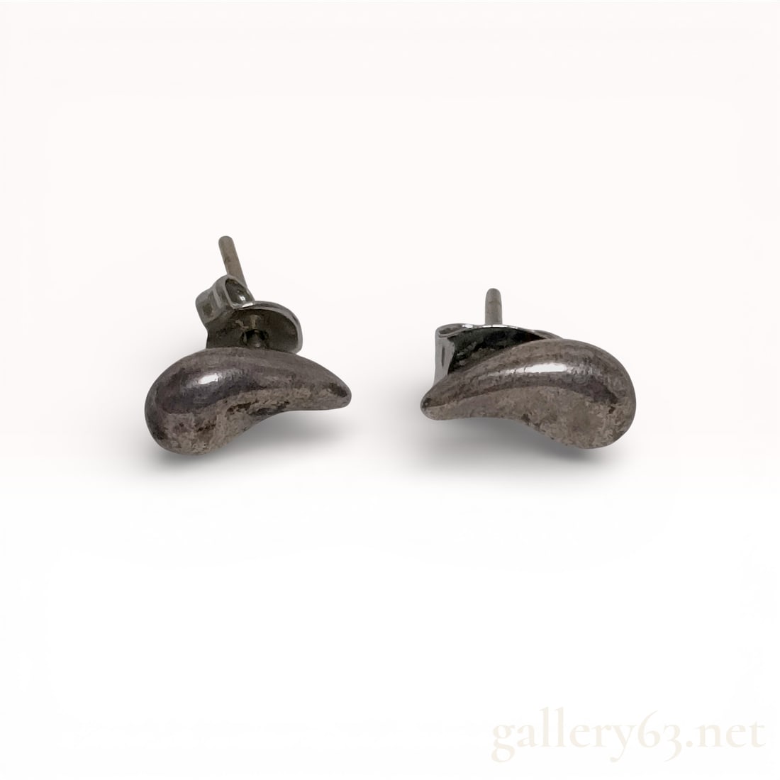 A Pair of Silver-Tone Bean Motif Stud Earrings: A matched pair of silver-tone metal stud earrings in an organic bean motif, resembling the Elsa Peretti design for Tiffany and Co. The earrings feature a polished, curved form and are secured with pos