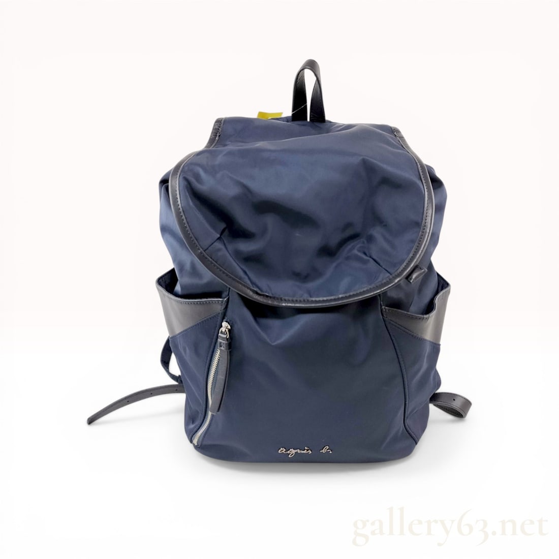 Agnes b. Voyage Navy Nylon and Leather Backpack: Agnes b. Voyage backpack featuring a navy blue nylon body with black leather trim and silver-tone hardware. The exterior is designed with a top flap closure, two side slip pockets, and vertical zipper