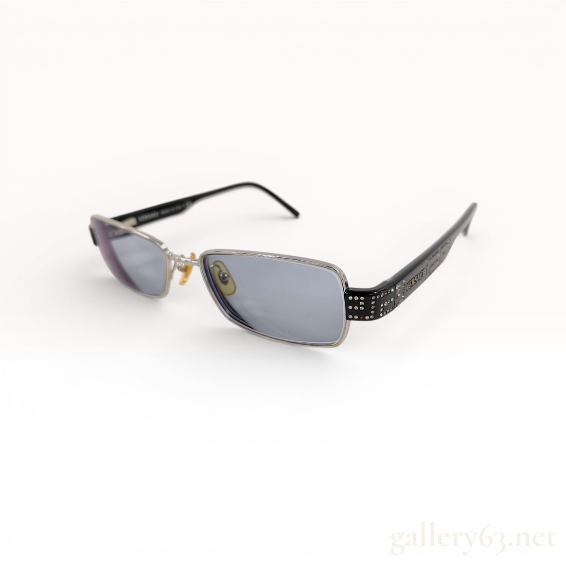 Versace Model 1093-B Rectangular Metal and Rhinestone Sunglasses: A pair of Versace rectangular sunglasses, model 1093-B. The frames feature a silver-toned metal front with a rectangular lens shape. The wide temple arms are made of black acetate and are decorated wi