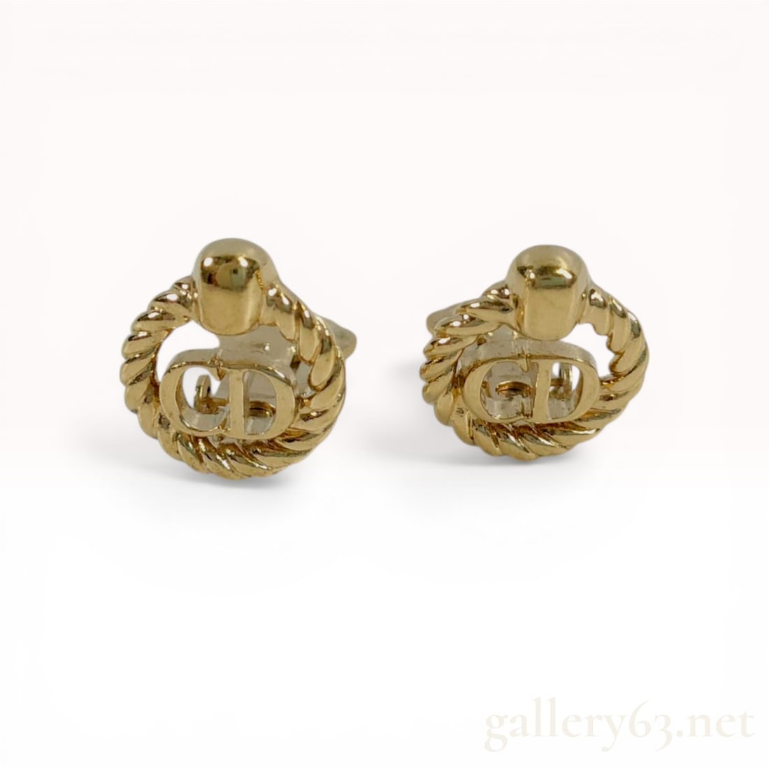 A Pair of Christian Dior Gold-Tone CD Logo Clip-On Earrings: Christian Dior vintage clip-on earrings featuring a central open-work CD logo. Each earring is crafted from gold-tone metal with a twisted rope-style border and a polished domed top element. The rever