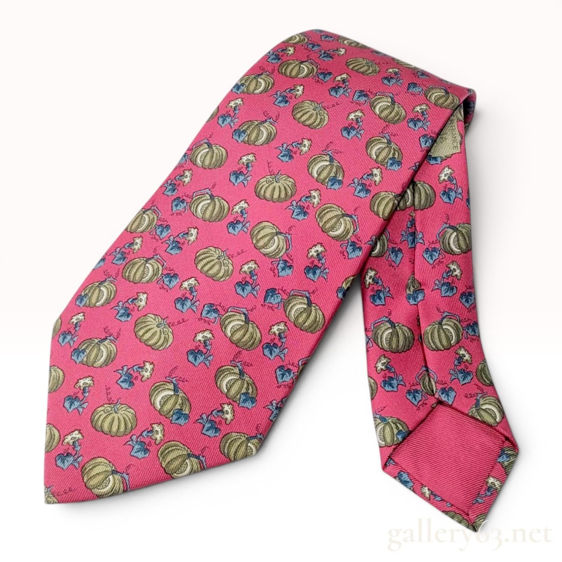 Hermes Silk Necktie with Pumpkin and Squash Pattern: A 100% silk necktie by Hermes featuring a novelty motif of stylized pumpkins or squash with scrolling vines and small blue and white flowers. The pattern is set against a raspberry pink ground. The re