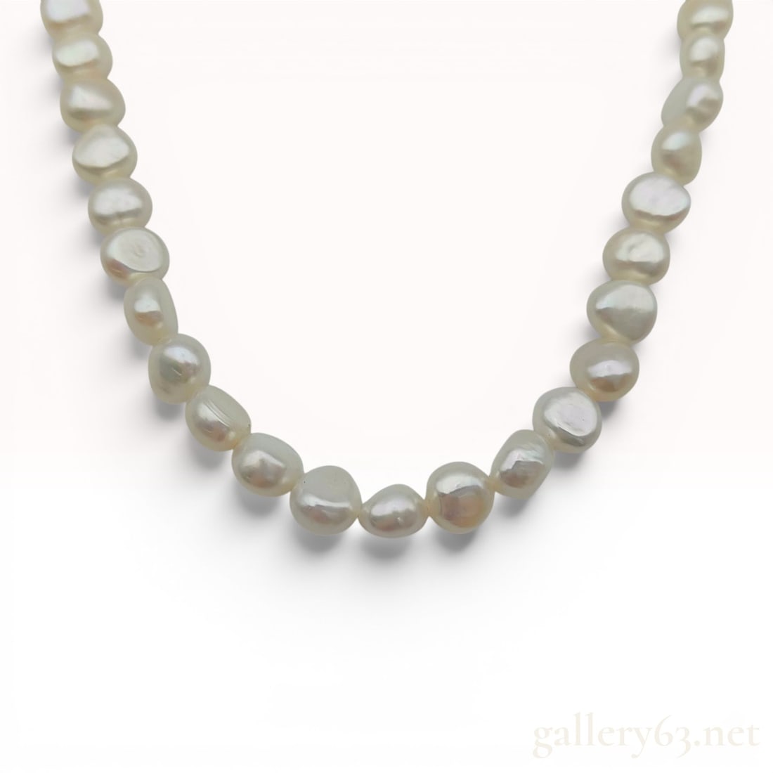 Cultured Baroque Pearl Necklace with Silver Floral Motif Clasp: A necklace featuring a strand of off-white to cream-colored cultured baroque pearls. The pearls are characterized by their irregular organic shapes, visible surface ridges, and good luster. The neckla