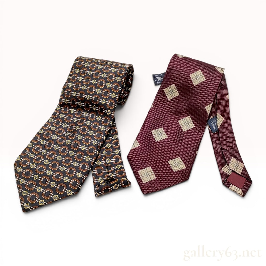 A Pair of Designer Silk Neckties, Fendi and Burberrys: This lot consists of two designer silk neckties. The first is a Fendi necktie featuring a repeating geometric chain-link motif in shades of brown and black. Interspersed within the pattern are blue an