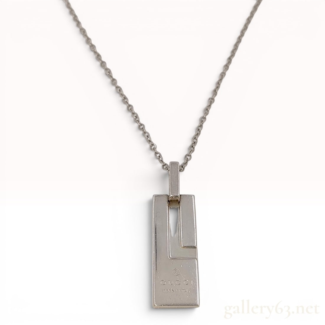 Gucci Sterling Silver G Plate Pendant Necklace: A sterling silver pendant necklace by the Italian luxury brand Gucci. The piece features a polished rectangular bar pendant with a geometric cutout design forming a stylized G logo. The pendant is sus
