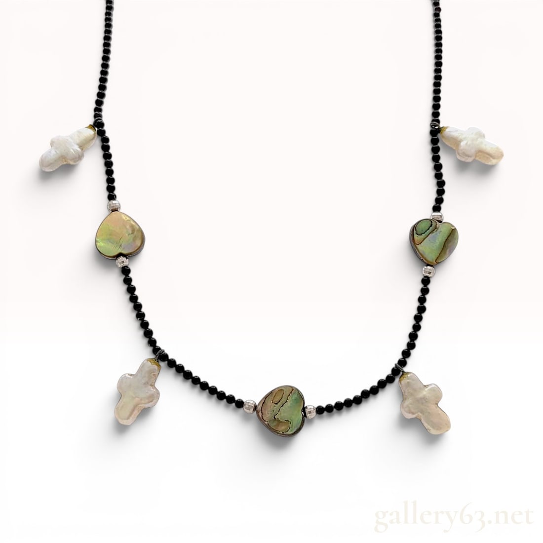 18K White Gold Abalone Heart and Baroque Pearl Cross Bead Necklace: Beaded charm necklace featuring a strand of small round black beads and 18 karat white gold accents. The strand is set with three heart-shaped iridescent abalone shell charms and four white cultured b