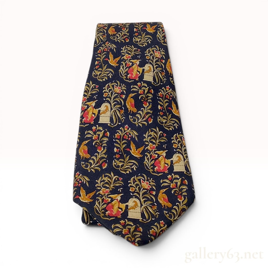Salvatore Ferragamo Navy Blue Silk Birdcage and Avian Print Tie: A designer necktie by Salvatore Ferragamo crafted from 100 percent silk. The tie features a whimsical repeat print on a navy blue ground, depicting figures in red and yellow attire tending to birdcage