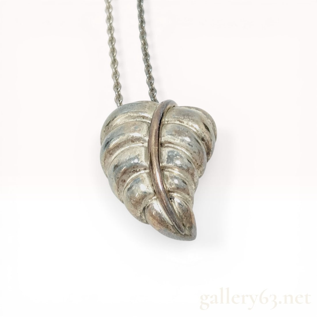 Tiffany and Co. Sterling Silver and 18k Gold Leaf Pendant Necklace: Tiffany and Co. sterling silver and 18k yellow gold leaf pendant necklace. The three dimensional pendant features a scalloped, ribbed leaf form with a contrasting gold toned central rib and a hollow r