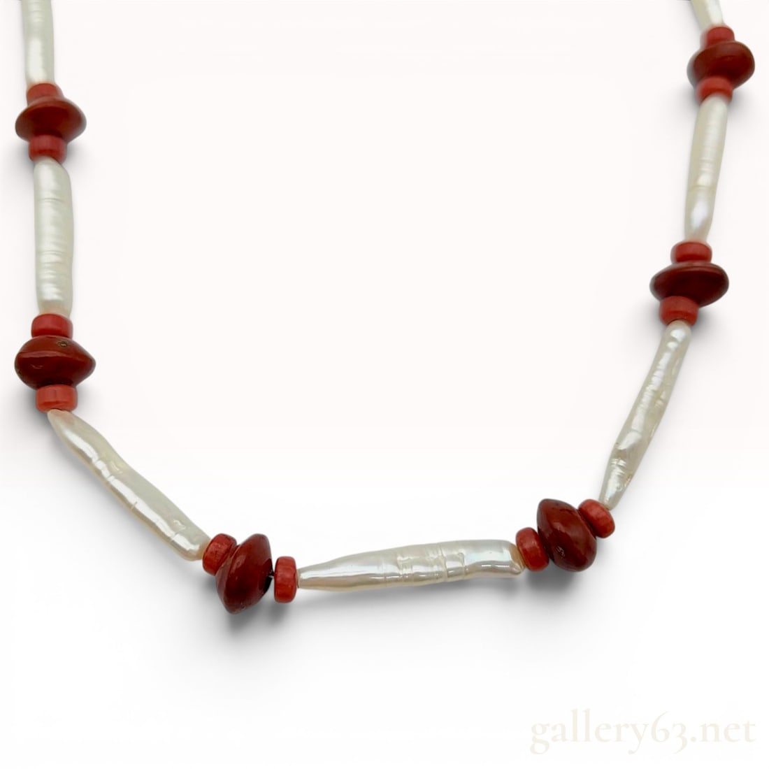 Freshwater Baroque Pearl and Antique Coral Beaded Necklace: This beaded necklace is composed of alternating elongated white freshwater baroque pearls, also known as Biwa style pearls, and red-brown stone beads in a bicone shape. Smaller red disc coral beads ar