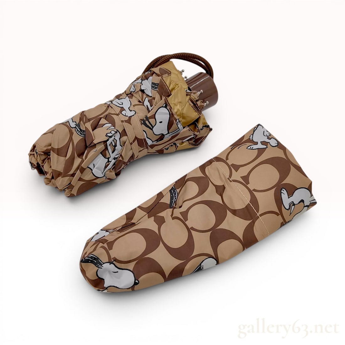 Coach x Peanuts Snoopy Signature Monogram Folding Umbrella with Matching Sleeve: This folding umbrella and matching storage sleeve are part of a limited-edition collaboration between Coach and Peanuts. The canopy is constructed from 100% polyester with a polyurethane coating. The 