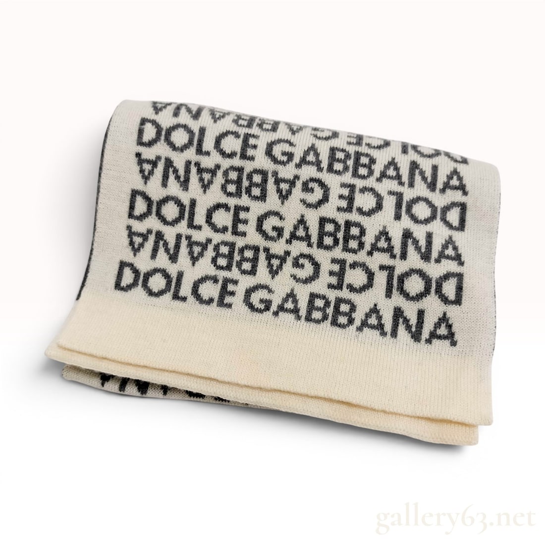 Dolce and Gabbana Reversible Logo Jacquard Scarf: A jacquard knit designer scarf by Dolce and Gabbana featuring a reversible logo-centric pattern. The design consists of repeated DOLCE and GABBANA text in a block font across the entire length of the 
