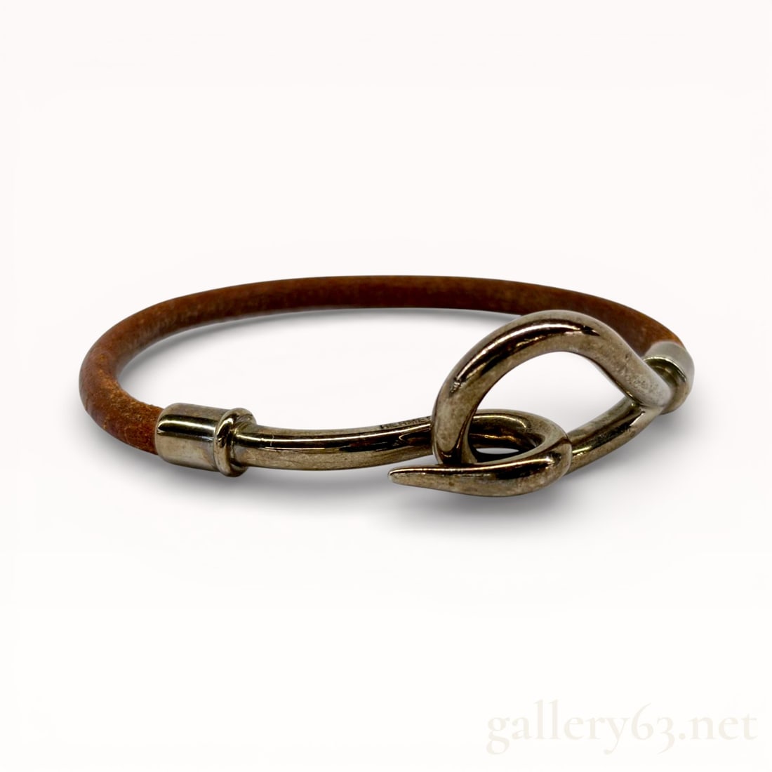 Hermes Jumbo Hook & Eye Bracelet Palladium-Tone: Authentic Hermes bracelet having a brown leather band with gold-tone metal hardware. Hook-style clasp featuring an oversized curved hook and loop closure. Cylindrical metal end caps securing the leath