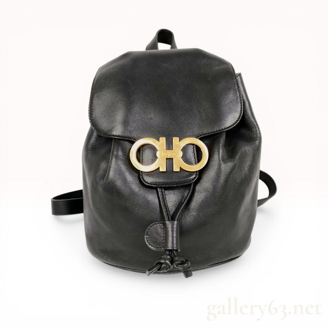 Salvatore Ferragamo Gancini Leather Backpack: Salvatore Ferragamo Gancini leather backpack. Crafted from smooth black leather, this bag features a front flap with a prominent gold-tone Gancini logo buckle and magnetic snap closure over a leather 