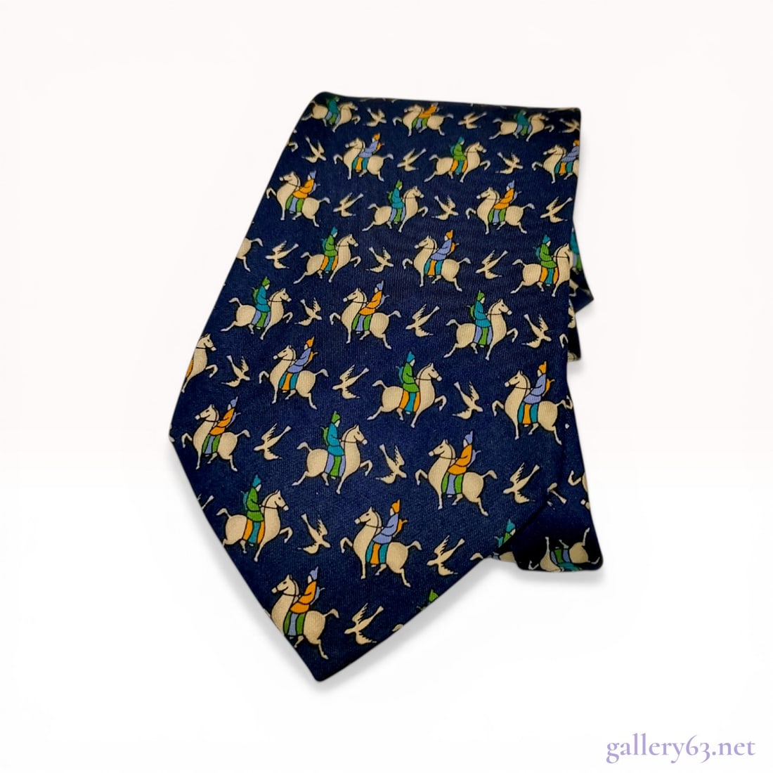 Salvatore Ferragamo Italian Silk Equestrian Motif Necktie: Salvatore Ferragamo silk necktie featuring a repeating equestrian pattern on a navy blue ground. The printed design depicts riders in green, blue, and yellow-orange jackets on white horses intersperse
