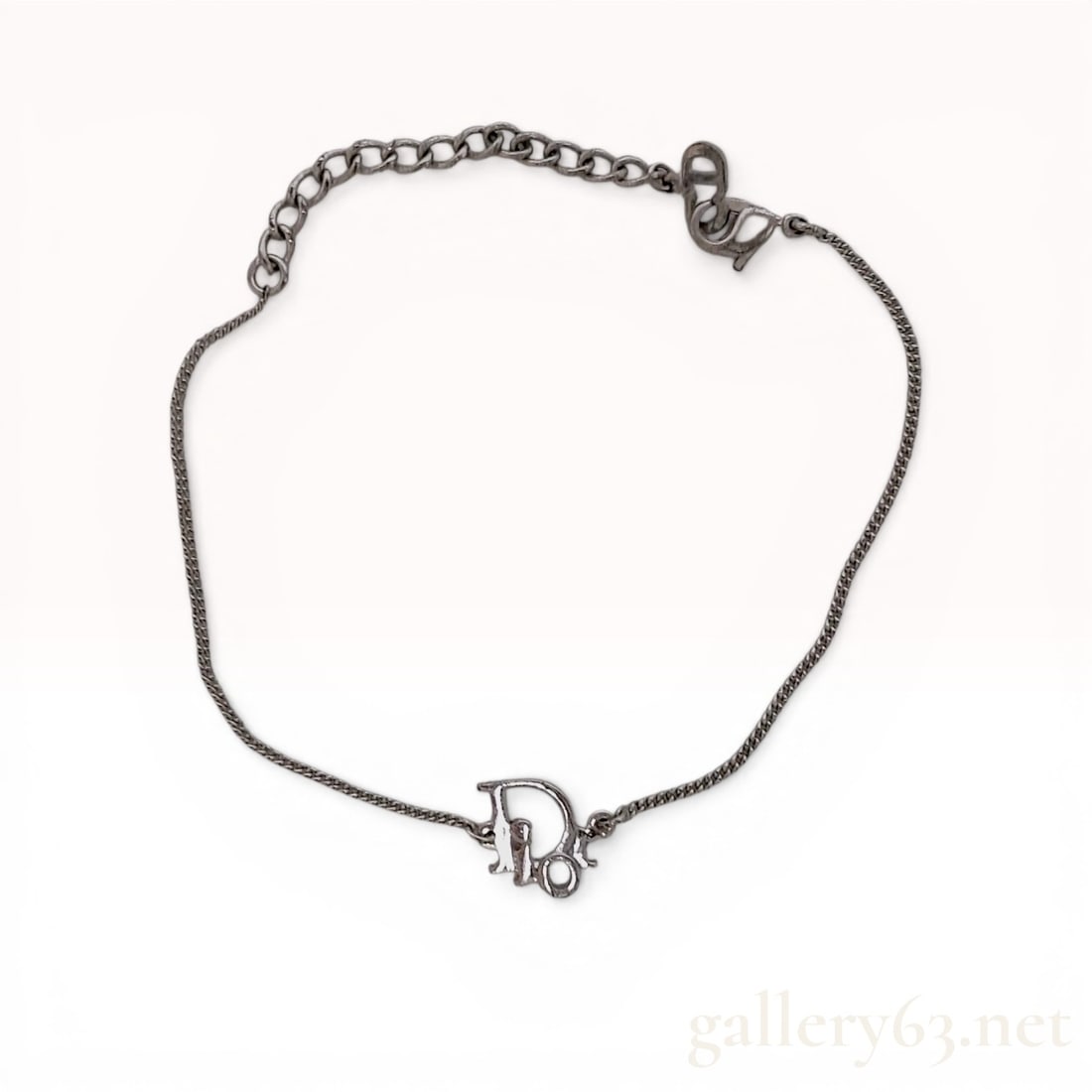 Christian Dior Silver-Tone Oblique Logo Chain Bracelet: Christian Dior silver-tone chain bracelet featuring a central openwork Oblique script logo charm. The piece is constructed with a fine curb link chain, a lobster claw clasp, and an extender chain term