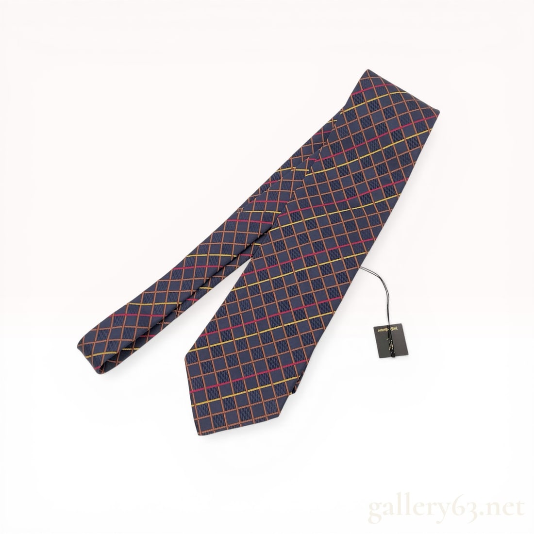 Yves Saint Laurent Silk Geometric Grid Pattern Necktie: Yves Saint Laurent men's necktie, manufactured in Japan under brand license. The tie features a geometric grid pattern with orange, tan, red, and yellow accents over a textured navy blue silk ground. 