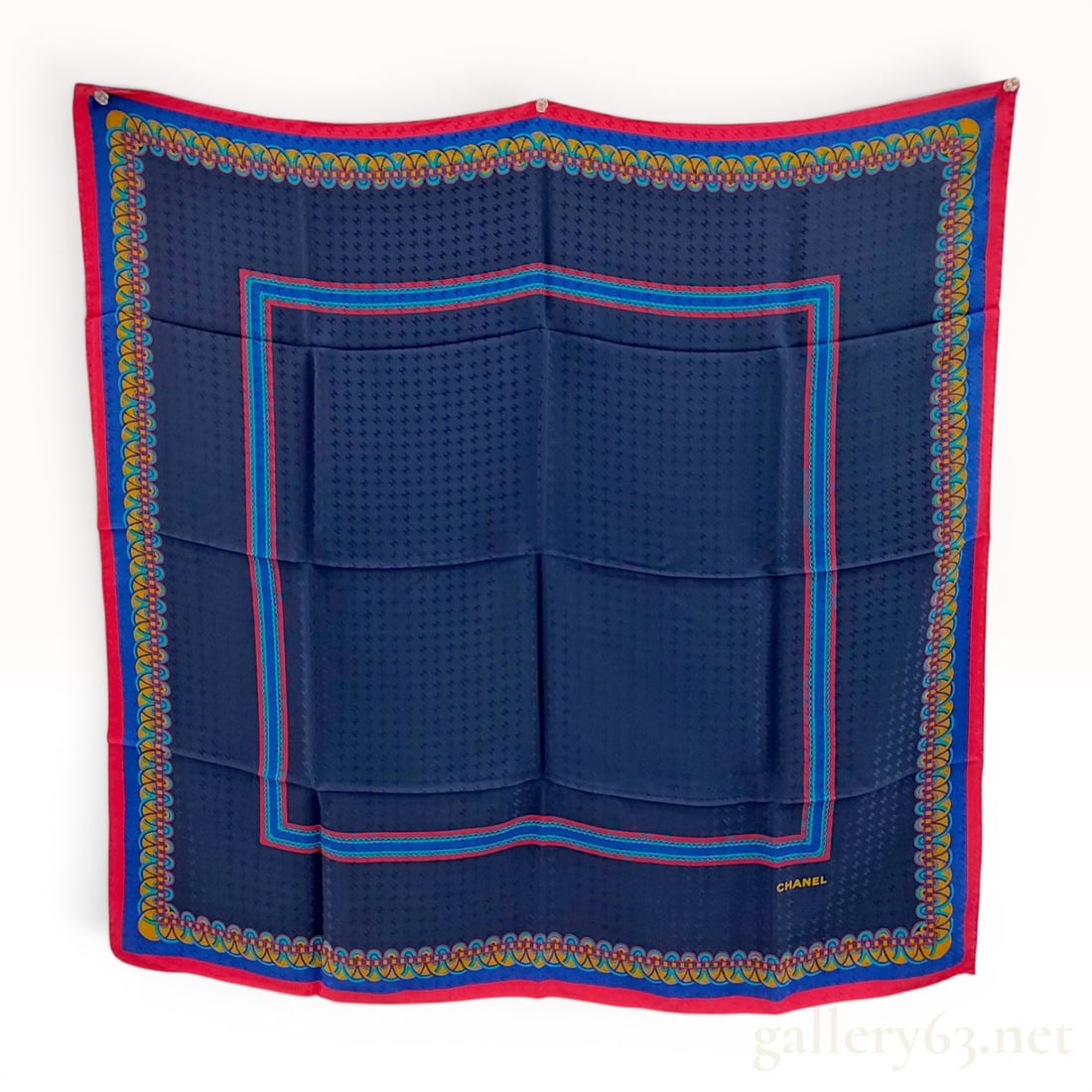 Chanel Silk Scarf with Tonal Logo Jacquard and Geometric Border: Chanel square silk scarf featuring a navy blue central field with an all-over tonal jacquard interlocking CC logo pattern. The field is framed by a multicolored decorative border with stylized link mo