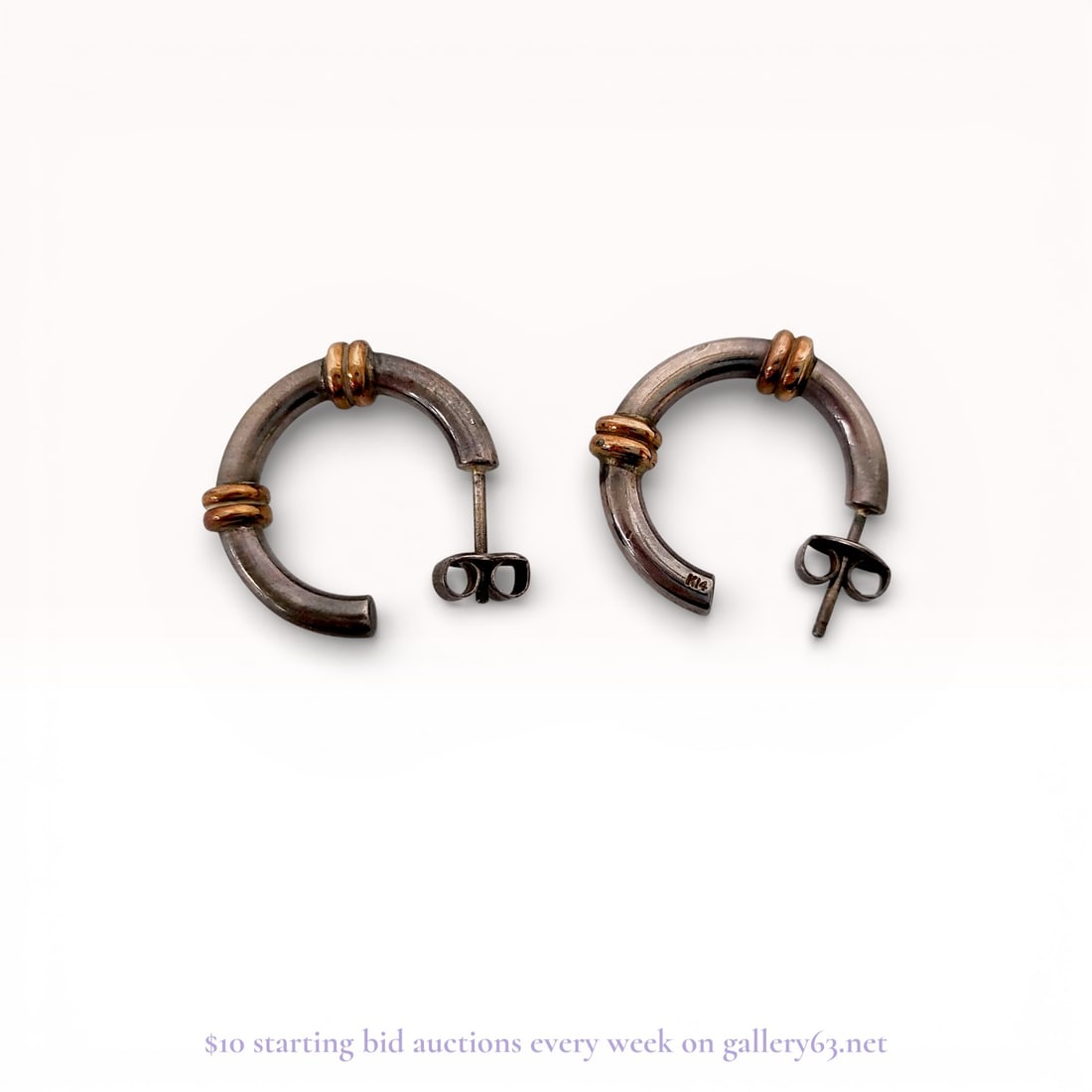 A Pair of Sterling Silver and 14 Karat Gold Two-Tone Hoop Earrings: A matched pair of C-hoop style earrings featuring a polished sterling silver body with two double-ribbed 14 karat gold accent bands. The design is characteristic of mid-to-late 20th-century American j