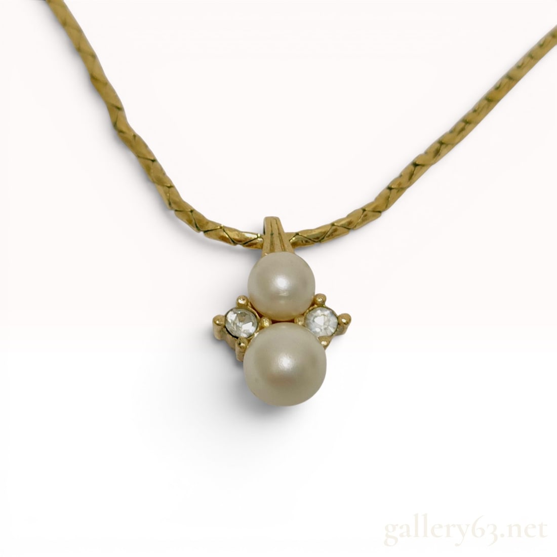 Vintage Christian Dior Gold Plated Faux Pearl and Rhinestone Pendant Necklace: A vintage Christian Dior pendant necklace featuring a gold-tone base metal construction. The necklace is designed with a flat chevron-link chain that suspends a fixed pendant. This pendant is set with