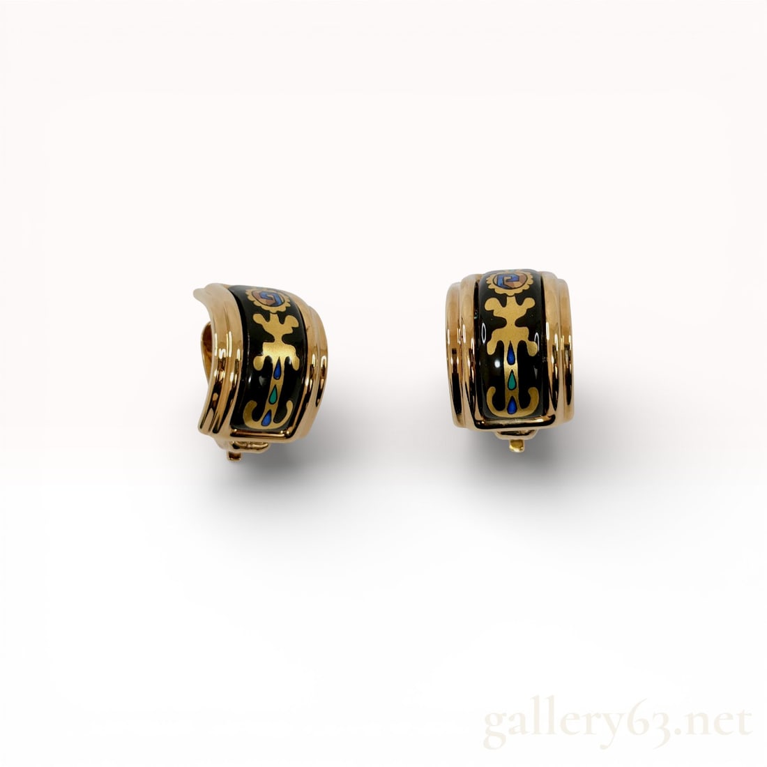 A Pair of Hermes Enameled Gold-Tone Clip-On Hoop Earrings: A matched pair of Hermes C-hoop earrings featuring black enamel inlays with stylized foliate patterns. The gold-tone metal frames house central panels decorated with scrolling gold-tone motifs and sma