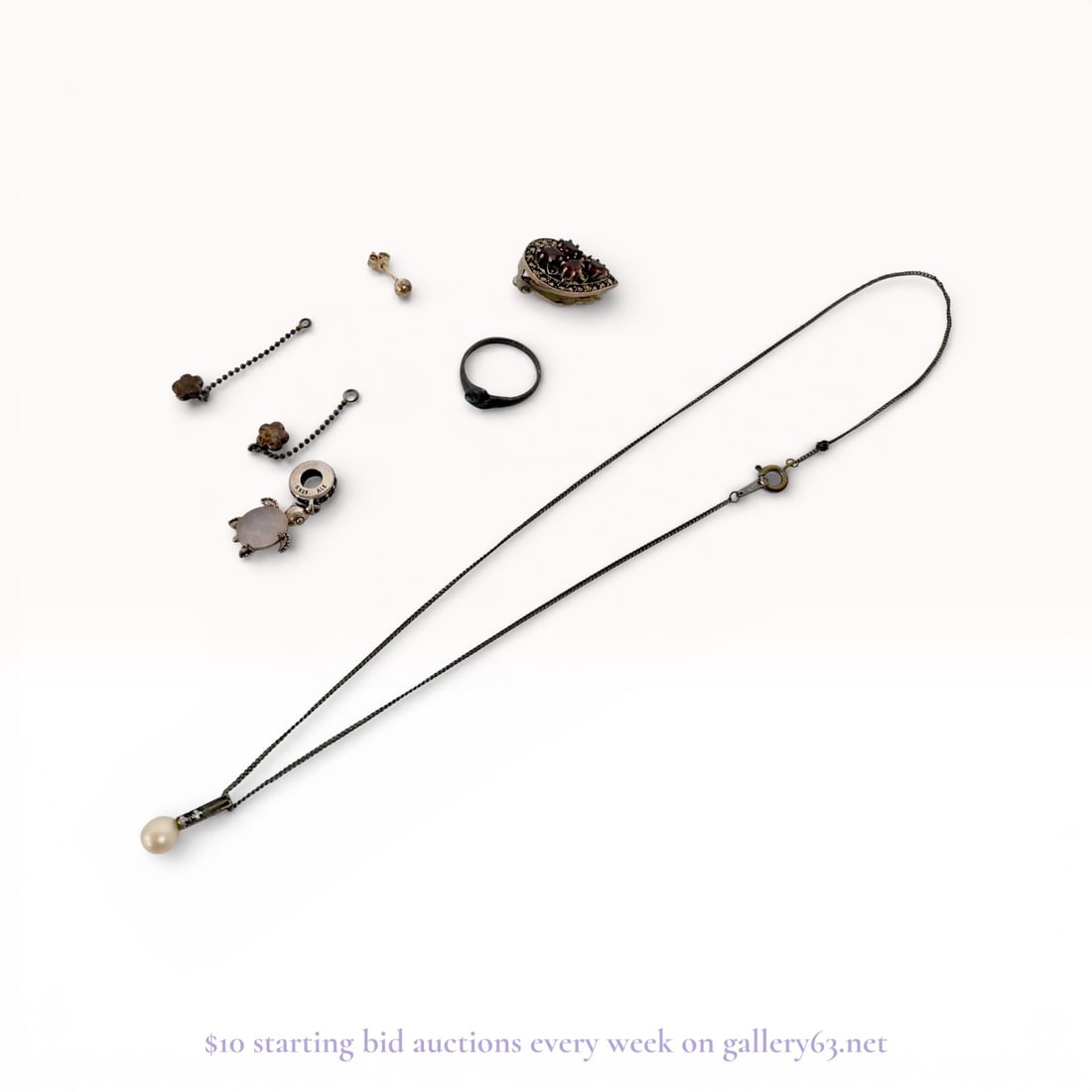 An Assortment of Sterling Silver and Costume Jewelry Including Pandora: An assortment of jewelry featuring a Pandora sterling silver turtle dangle charm and two Scandinavian sterling silver flower charms. The lot includes a teardrop-shaped marcasite and red stone clip-on 