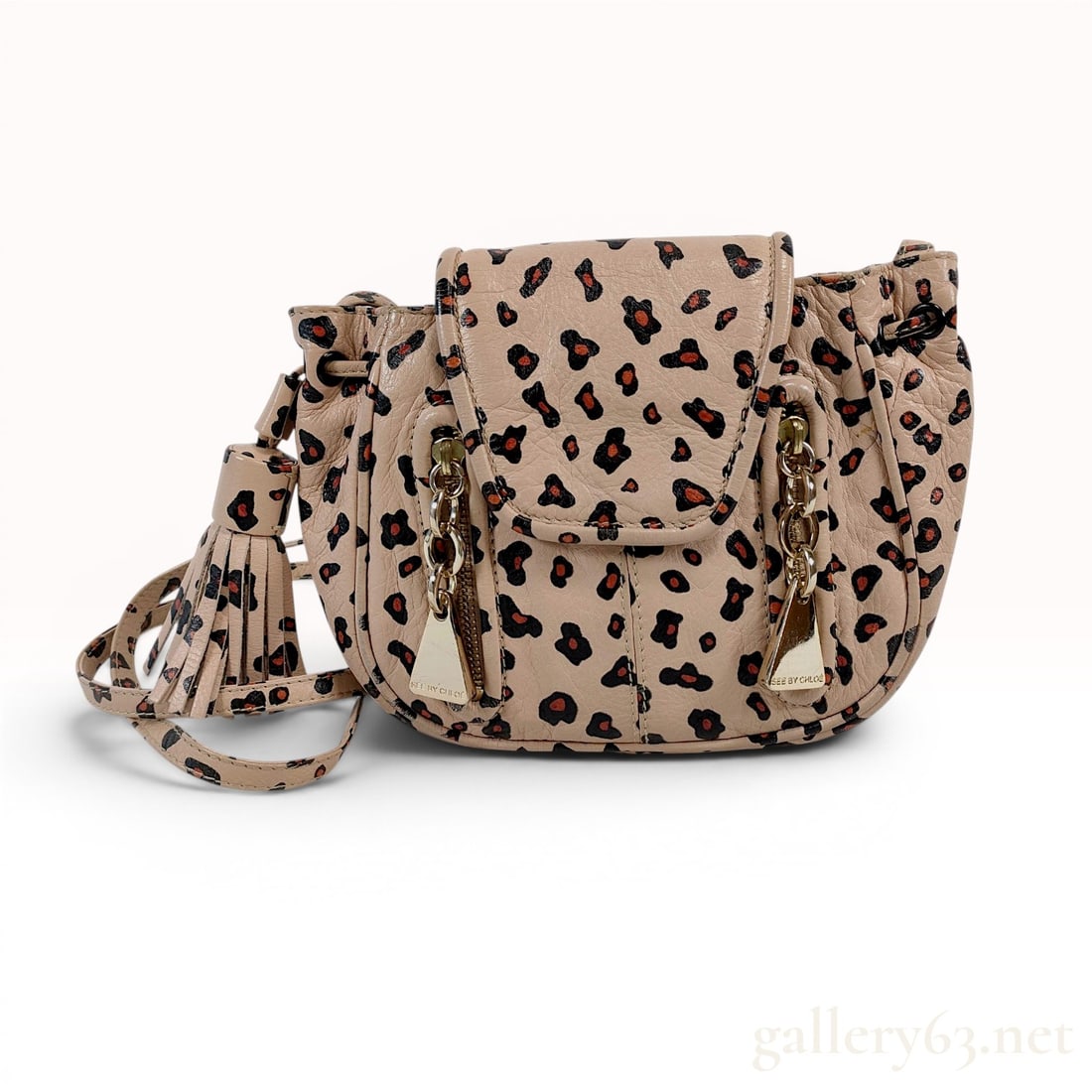 See by Chloe Mini Cherry Leopard Print Leather Crossbody Bag: See by Chloe Mini Cherry crossbody bag crafted in leopard print pebbled leather with a dark fabric interior. The design features a magnetic snap flap, a drawstring closure, and two front zippered pock
